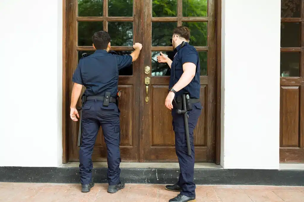Two police officers knocking on a front door